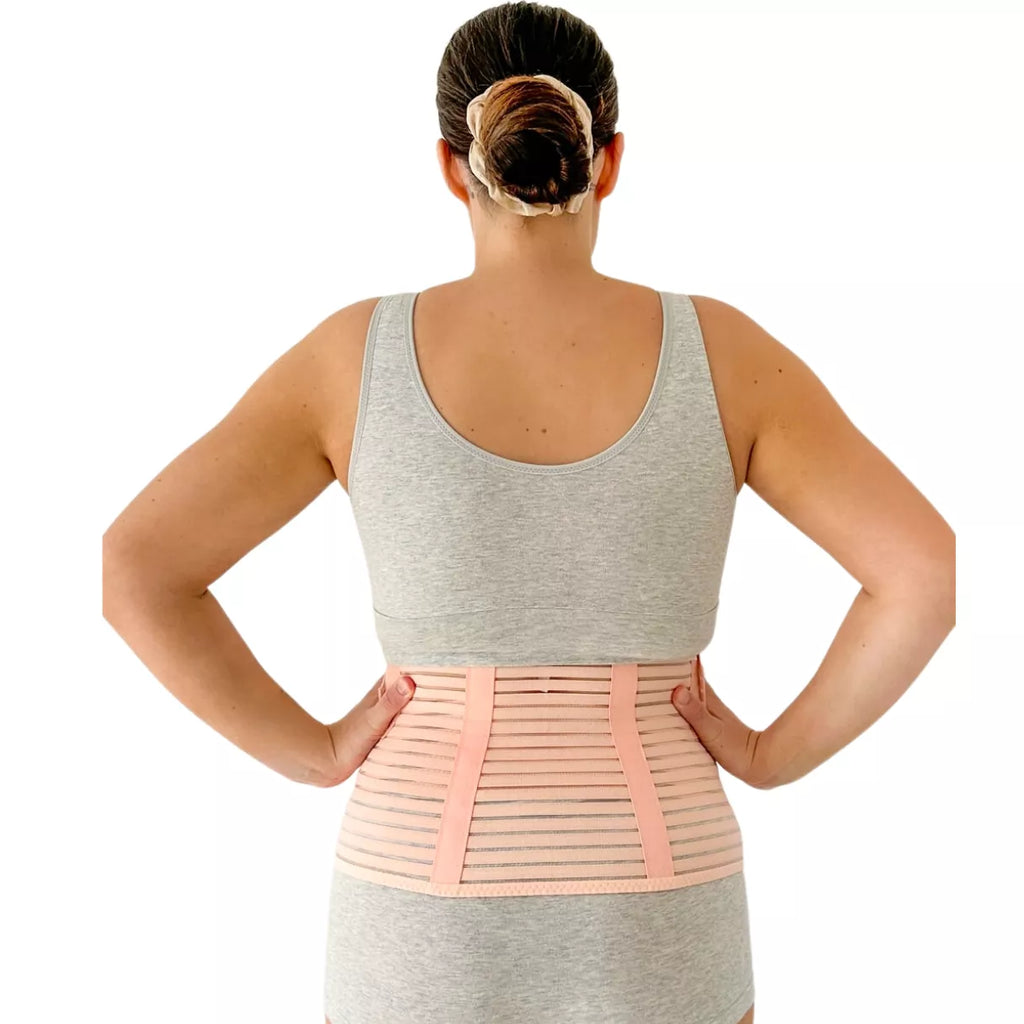 Woman wearing a beige belly support  girdle  back view on a white background.