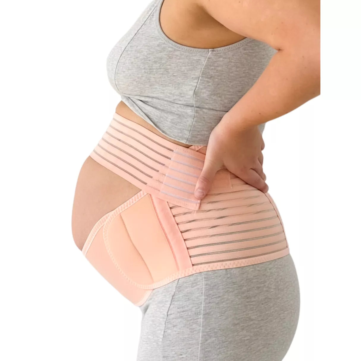 Pregnant woman wearing a beige belly support band on a white background.